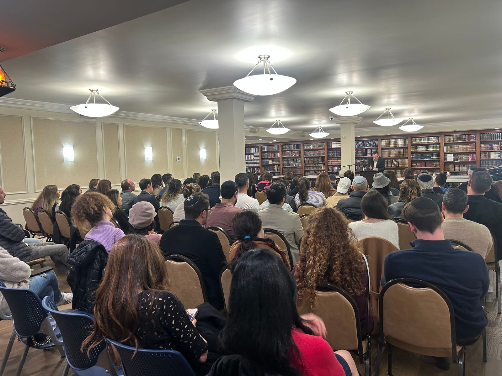 A full study hall of seated guests facing the front of the room.